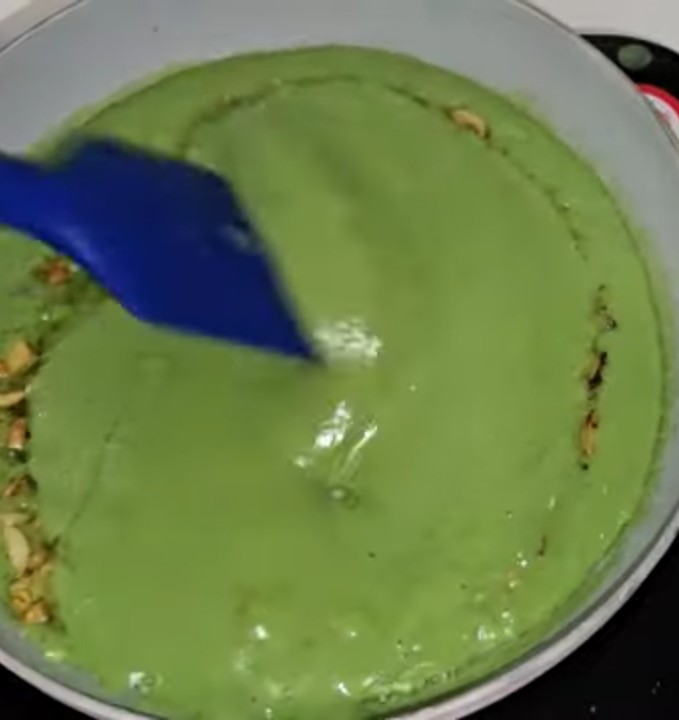 Mixing creamy green soup with a spatula in a pan on the stove